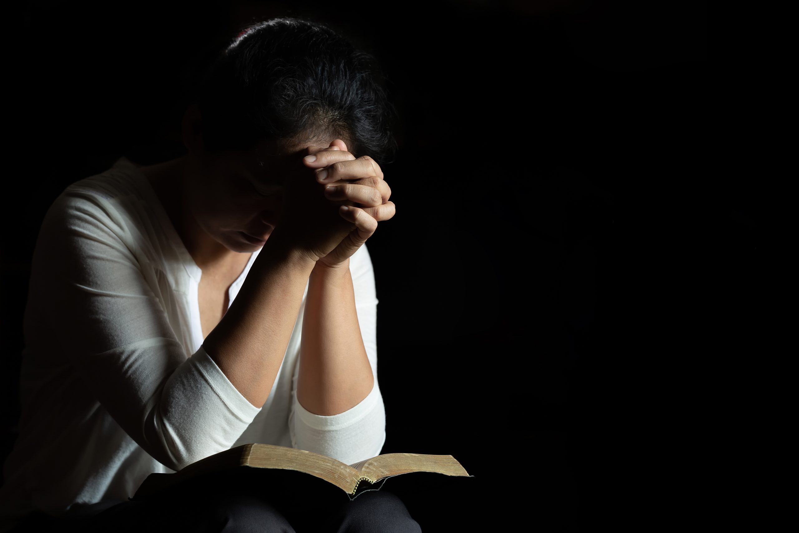 Hands folded in prayer on Bible